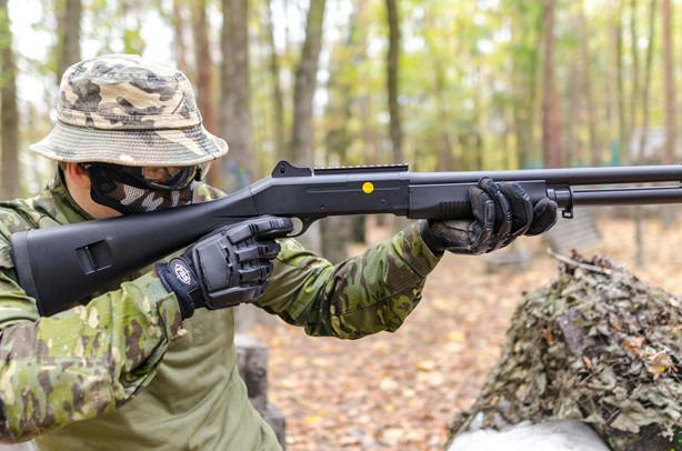 a person holding a shotgun with black field gloves